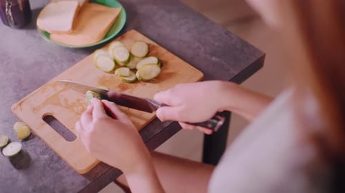 Woman Preparing Food, Slicing Cucumber on Board