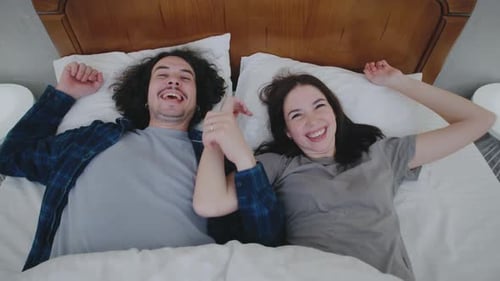 A Cheerful Couple Playfully Falls Onto a Bed Laughing Together Their Spontaneous Energy and