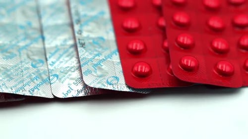 Packs of Red and Silver Medication on White