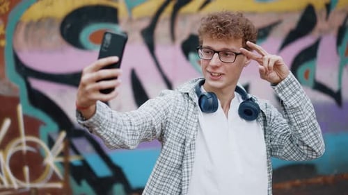 Smiling Young Adult Taking Selfie Near Graffiti Art