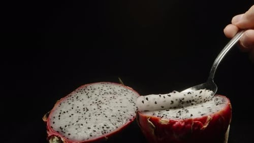 I scoop out the white pulp from the pitahaya with a spoon and carry it to the camera. Close-up on a