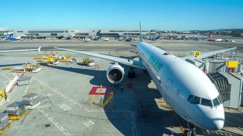 A Large Passenger Airplane is Docked at a Gate Surrounded By Ground Service Vehicles
