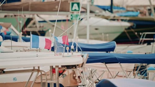 Un port de plaisance animé rempli de voiliers, de auvents et de drapeaux français, créant un motif superposé de bleu