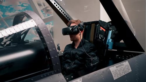 guy sitting in flight simulator of military plane wearing virtual reality glasses during flight