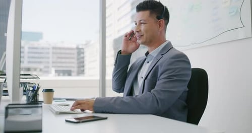 4k video footage of a young businessman wearing a headset while working on a computer in an office