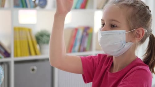 Child Wearing Mask Raising Hand in Classroom