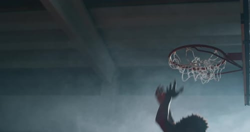 Cinematic slow motion shot of an young african professional male player is making a slam dunk duri