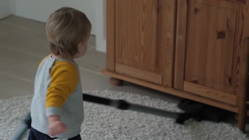 Blonde Child Playing with a Vacuum Cleaner Indoors