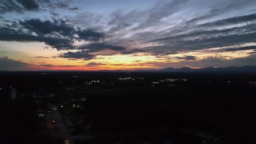 Mystic golden sunset at horizon over dark american city with deriving car on road. Aerial panorama
