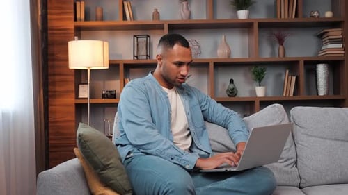 Relaxed Guy Student Freelancer Using Laptop Sitting on Sofa at Home Office