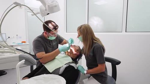 Treatment of Teeth in a Modern Dental Clinic Dentist with Assistant Treating a Patient's Caries
