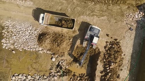 Excavator Loading Dirt into a Truck: Aerial Shot