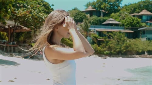 Smiling Female Model in White Swimsuit Posing on Sandy Beach