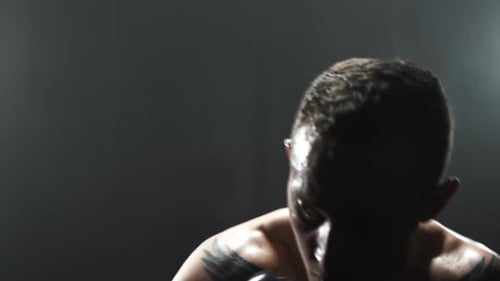 Boxer ferociously punching a boxing bag during his training,dark gym.