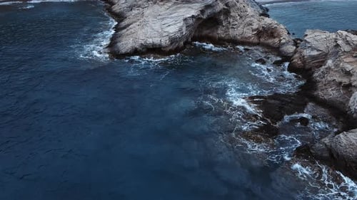Rocky reef and sea water waves crashing cliff