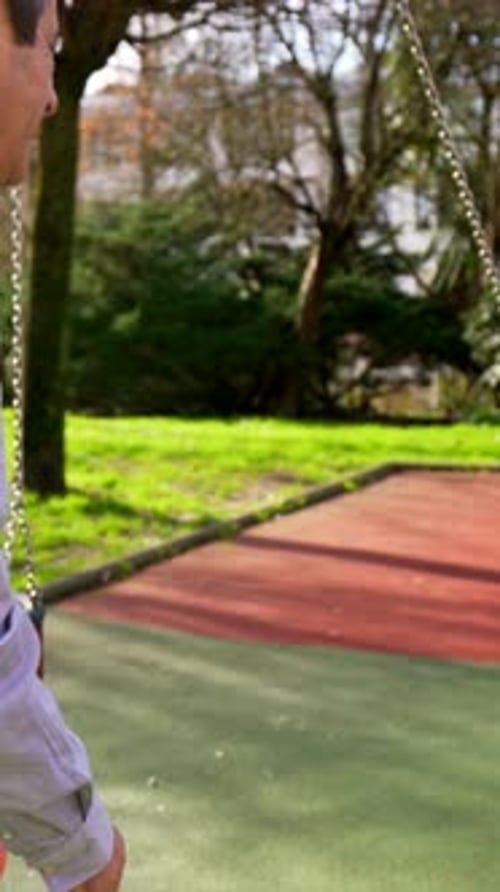 Grandfather Pushing Grandson on a Swing in the Park