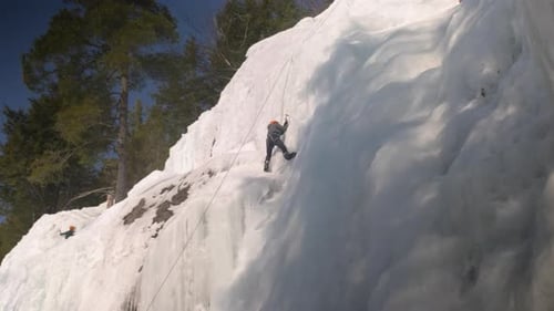 Wide angle view of a determined ice climber reaching the summit of a ice wall