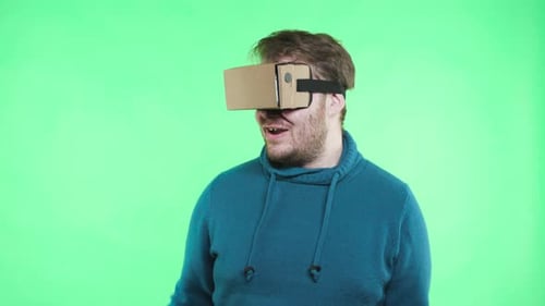 Trendy guy joyful moving in vr glasses connected to mobile phone green screen