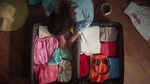 Woman Organizing Clothes and Packing Suitcase for Trip