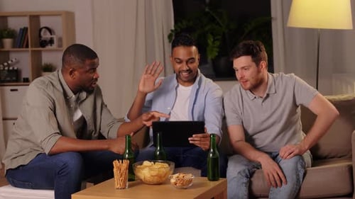 Male friends enjoying video call with beer at home late at night