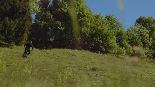 Amazing shot of MTB E-biker biking down the hill in the nature. Extreme rider is having fun.