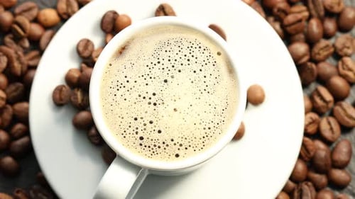 Aromatischer Kaffee in Tasse und Bohnen auf dem Tisch, flach liegend