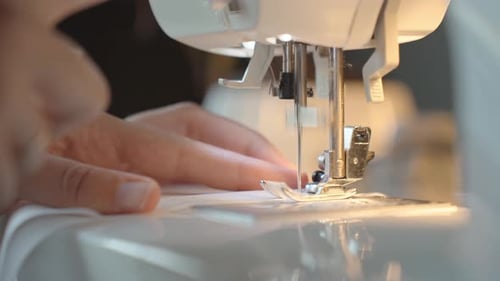 Close up of female hands using sewing machine to sew fabric