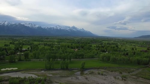 Green Landscape with Snow Capped Mountains in the Background by Aerial Drone Barn