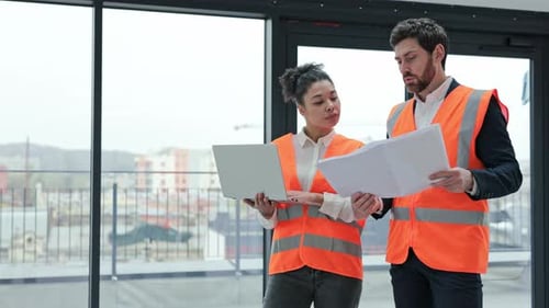 Arquitetos revisando plantas e discutindo detalhes do projeto no canteiro de obras