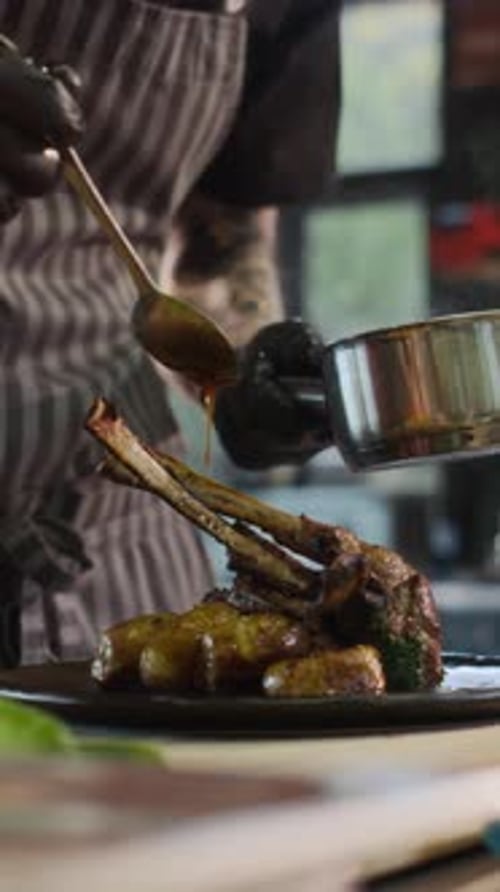 Close Up Man Adding Sauce To Lamb Rack Vertical