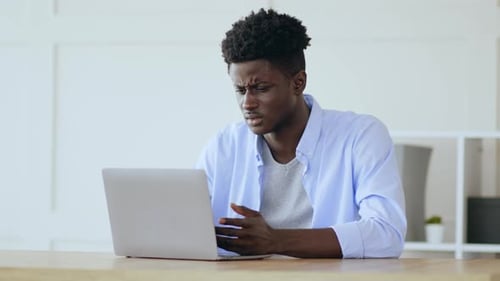 Afrikanischer Manager schaut sich Laptop mit Verbindungsproblemen an