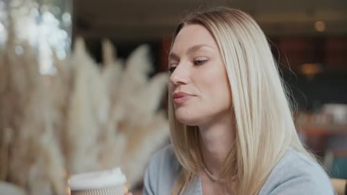 Close Up Attractive Charming Blond Young Woman Sits and Enjoys Drinking Coffee Sitting in Cafe
