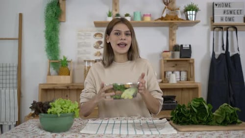 Smiling Woman Presents Healthy Salad in Bright Kitchen