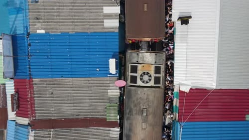 Aerial Top Down View of Train Passing Mae Klong Railway Market, Thailand. Tourists Dangerously Huddl