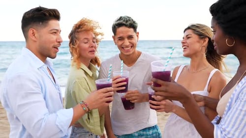Friends toasting and drinking smoothies on the beach
