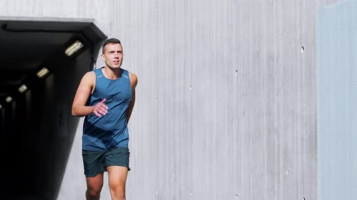 Young man running out of tunnel in slow motion fitness training workout