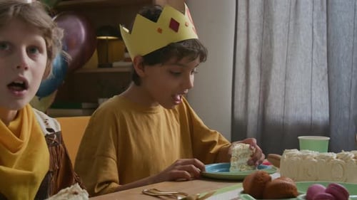 Boy Eating Piece of Cake with his Hands During Children Birthday Celebration