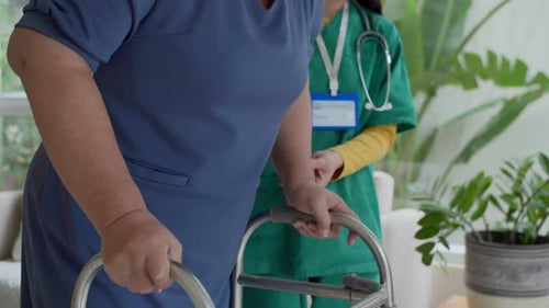 Elderly Woman Uses Walker with Healthcare Assistant