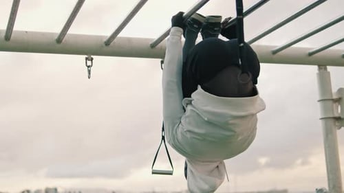 A young athlete pulls himself up on a horizontal ladder, street workout
