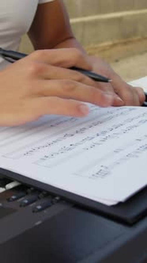 Person Writes Music On Sheet