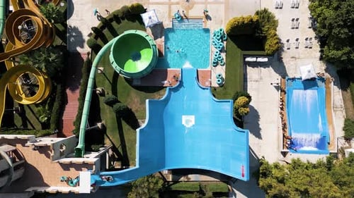 Aerial View of a Colorful Water Park with Multiple Slides Pools and People Enjoying Summer
