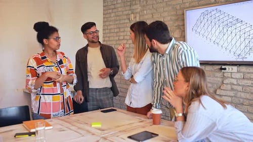 Group of young business people discussing architectural designs in office.