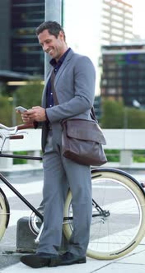Businessman, phone and texting with bike in city for commute, smile and thinking on trip Person