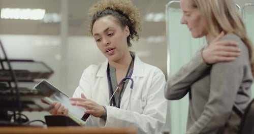 Doctor talking to Patient in Doctors Office about Medical X-ray on Digital Tablet