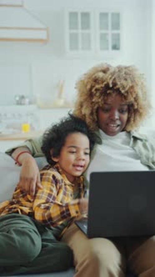 Little Boy Cuddling with Mom and Watching Cartoon on Laptop at Home