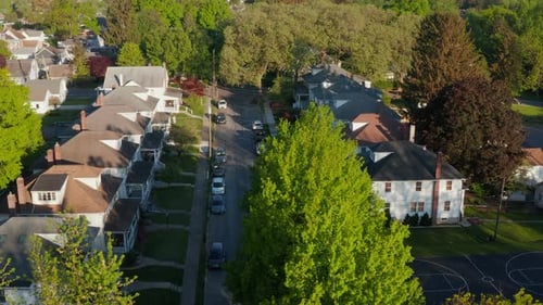 Aerial establishing shot of quiet neighborhood town. Homes in summer. Tilt up drone shot.