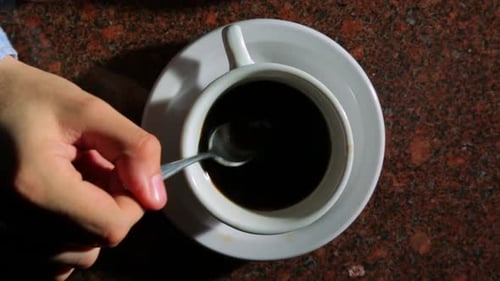 Close-Up of Hand Stirring and Lifting Coffee Cup to Drink