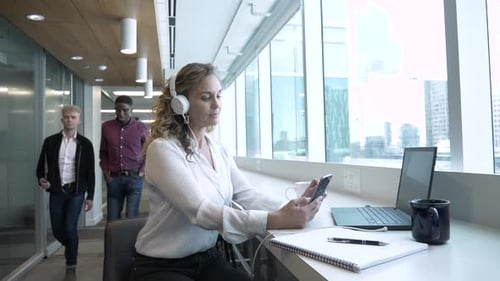 Businesswoman with Headphones Working in Highrise Office Adult