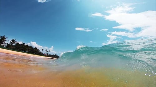 Ocean wave breaks over the sandy tropical beach