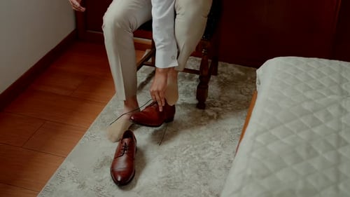 Man Tying Dress Shoes in Hotel Room